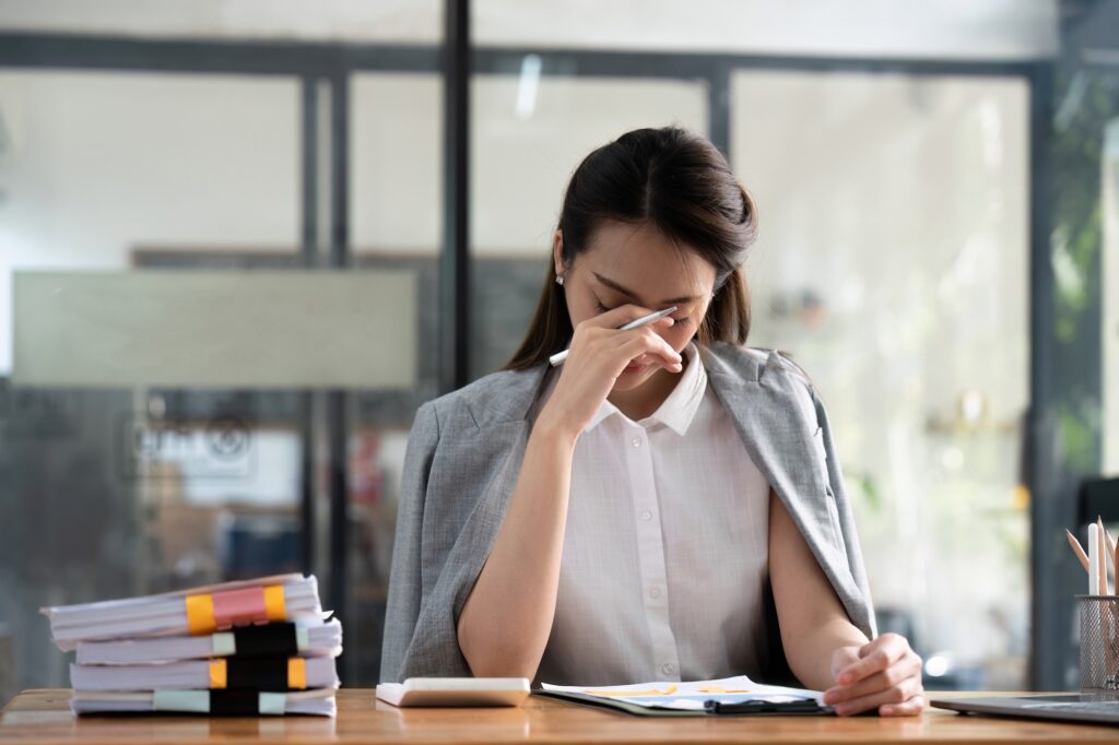 Stressed business woman working from home on laptop looking worried, tired and overwhelmed